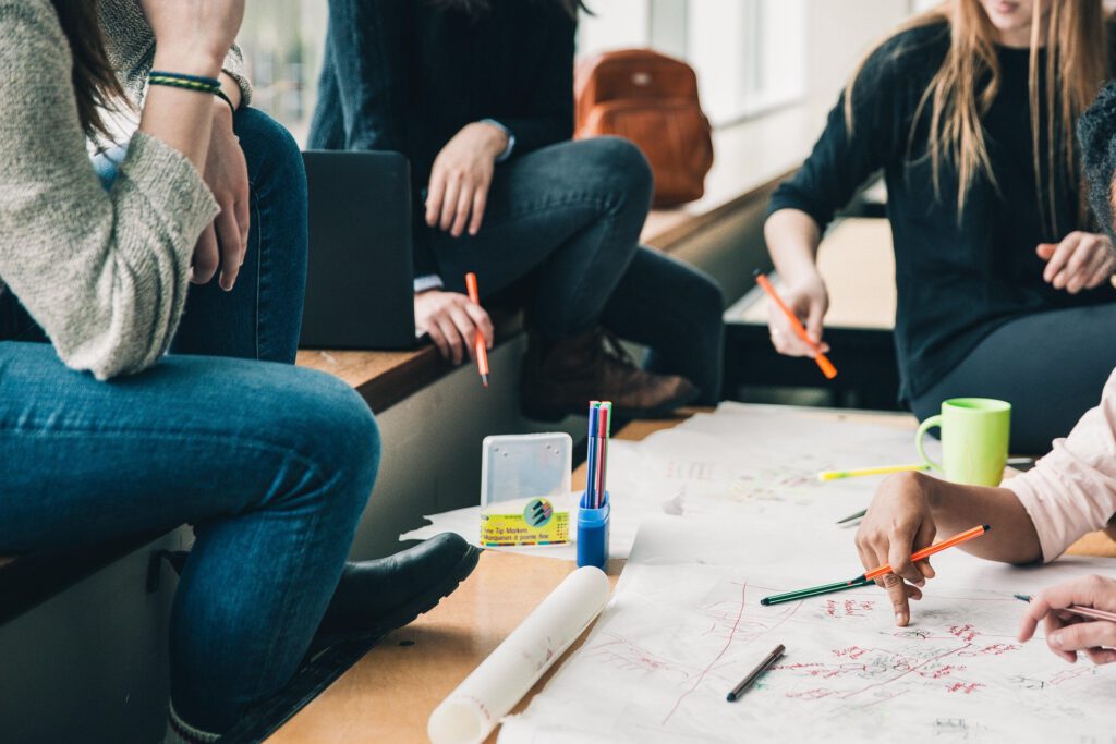 Freunde sitzen zusammen und planen mit Papier und Stiften auf dem Tisch