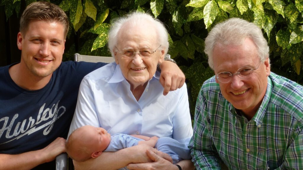 Mehrgenerationen - Baby, Vater, Großvater und Urgroßvater sitzen zusammen
